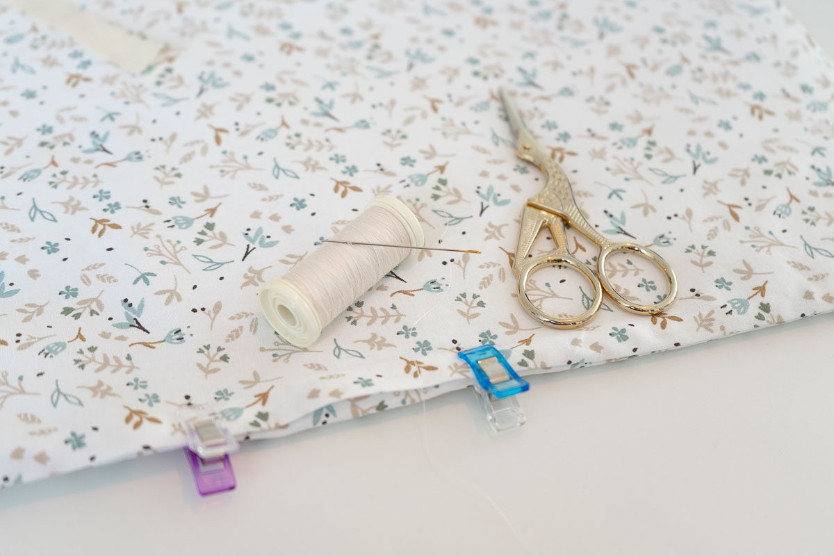 couture-illustration Focus photo sur un tissu, un ciseau de couture et une bobine de fils beige.