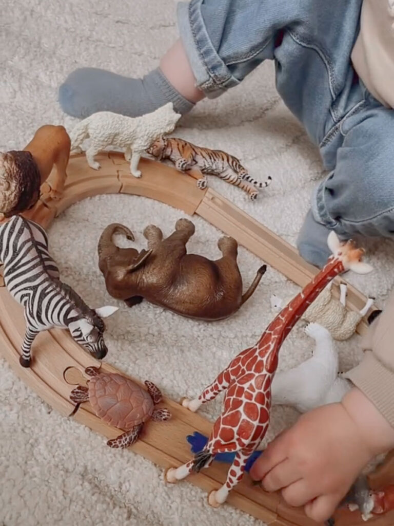 enfant-qui-joue Enfant qui joue avec un circuit en bois et des animaux